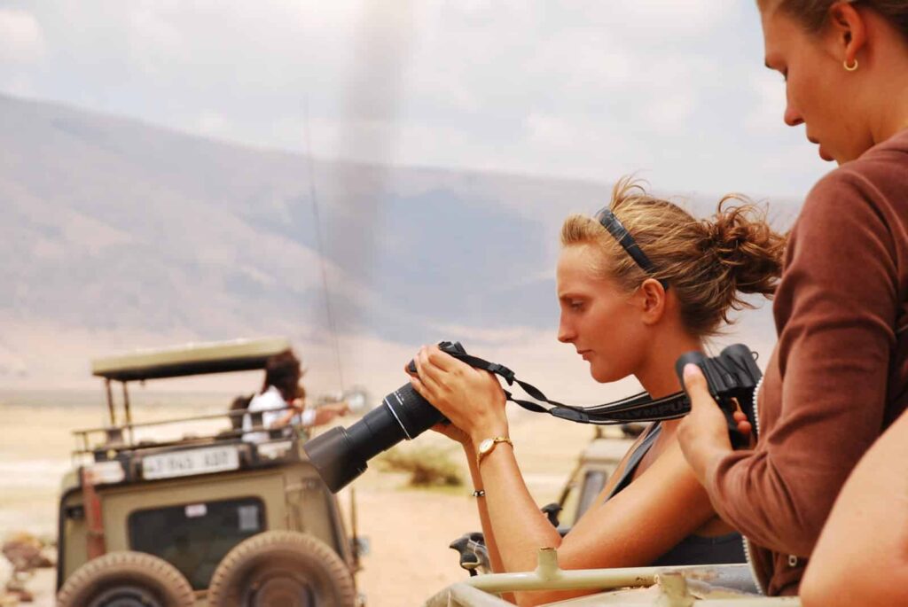 På safari adventur tur og observerer dyreliv gennem kikkert fra jeep i åbent savannelandskab, med fokus på oplevelse, natur og eventyr.